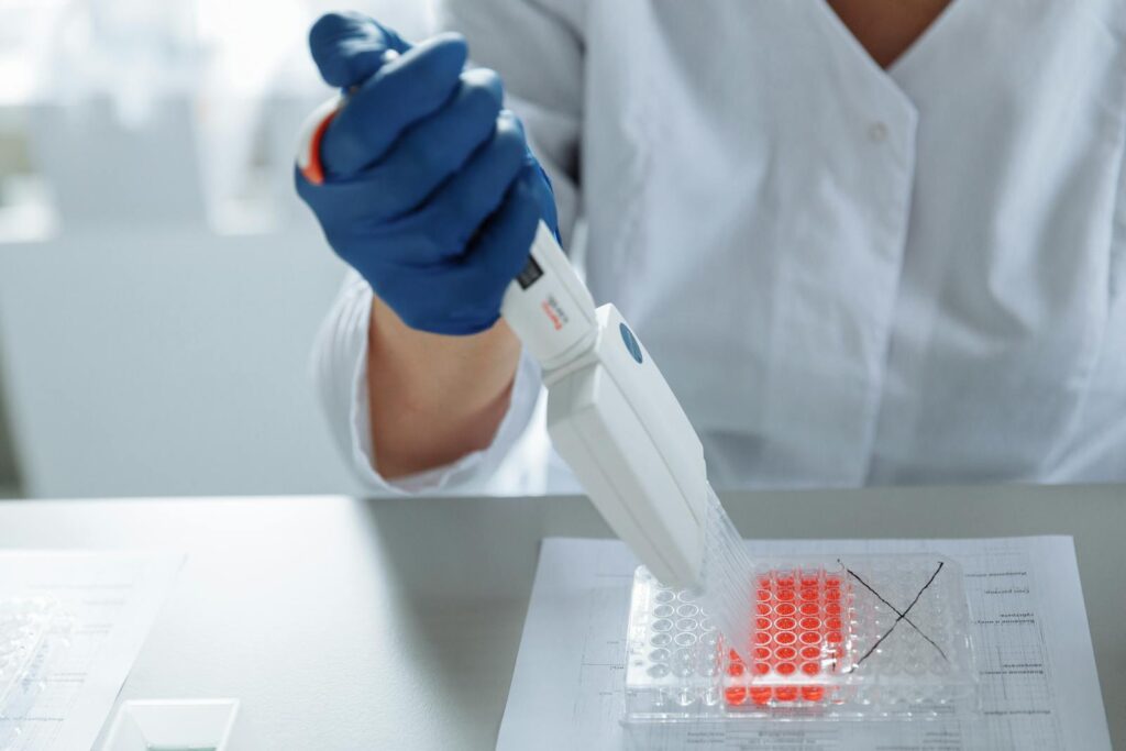 Close-up of a scientist using a pipette in a lab with a focus on sterile procedures.